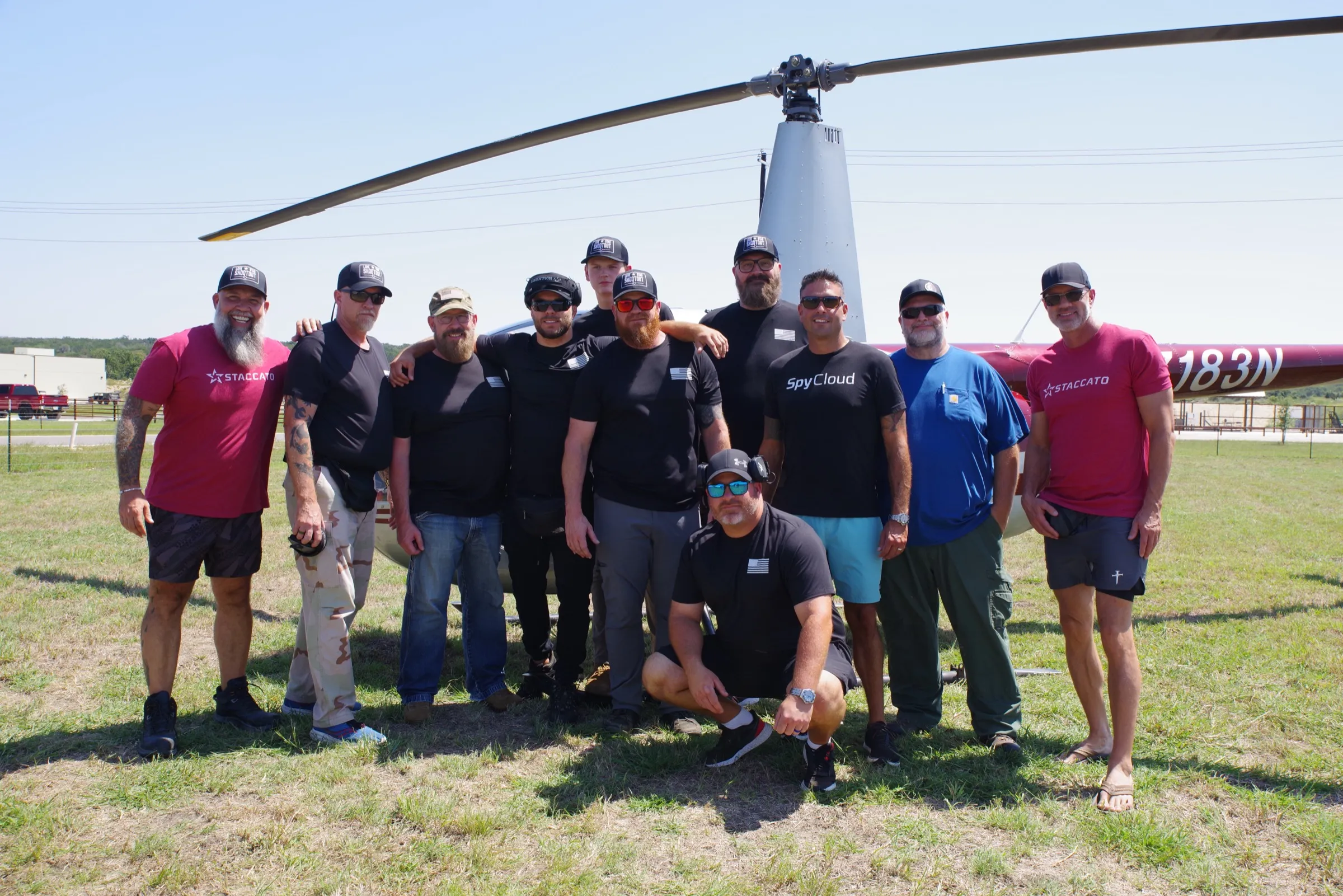 Group of participants posing together in front of a helicopter after a gunnery flight